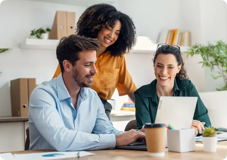Three professionals collaborating around a laptop in a bright modern office